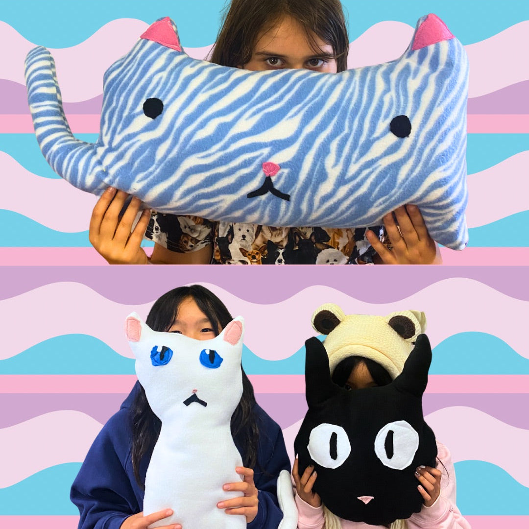 Three people holding cat-shaped plush toys against a colorful striped background