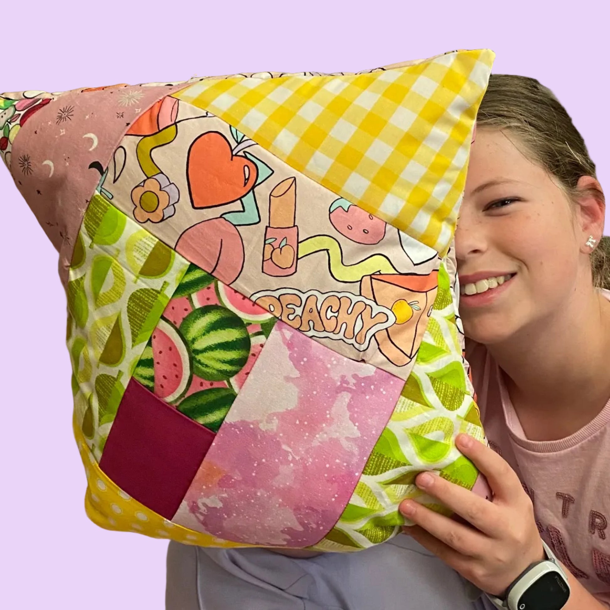 Person holding a colorful patchwork pillow with cartoon designs